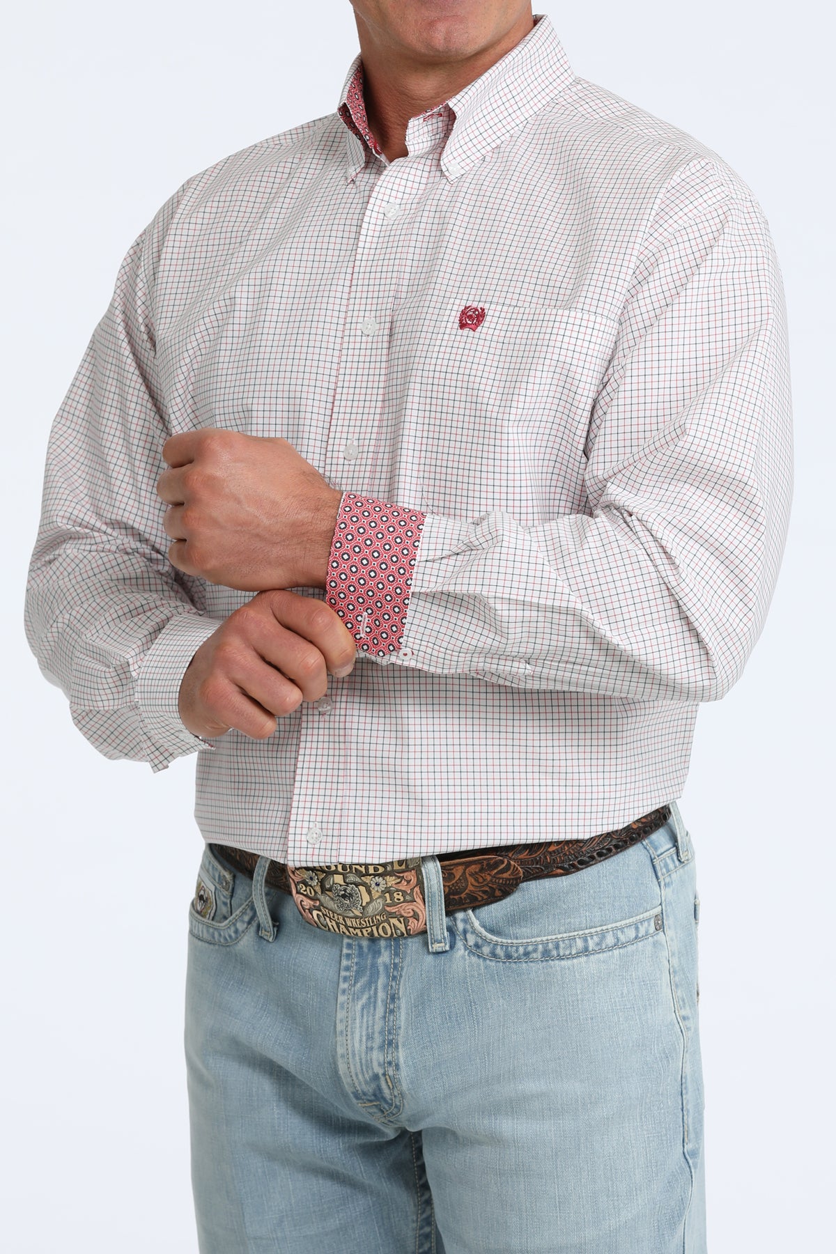 Man wearing a patterned shirt with rolled-up sleeves and light blue jeans on a white background