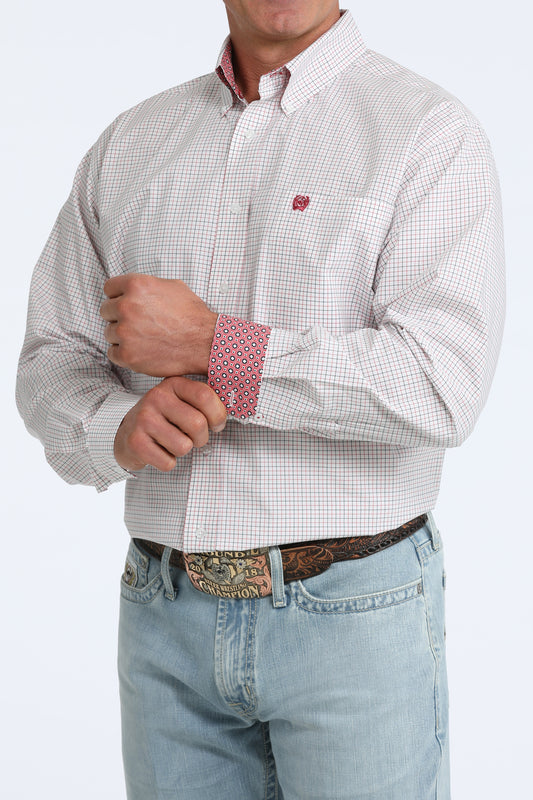 Man wearing a patterned shirt with rolled-up sleeves and light blue jeans on a white background