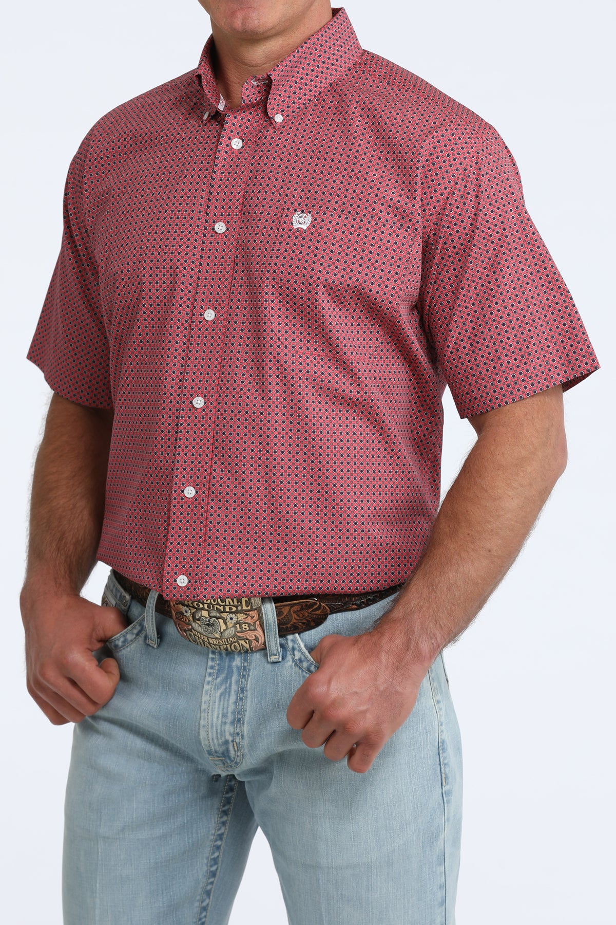 Man wearing a red patterned shirt and light blue jeans on a white background