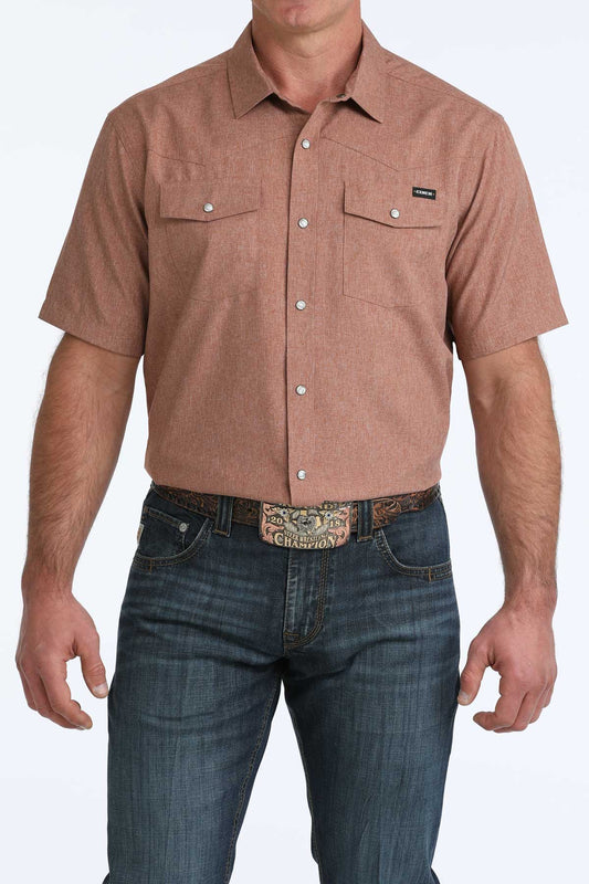 Man wearing a brown short-sleeve shirt and blue jeans on a white background
