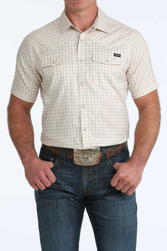 Man wearing a beige checkered short-sleeve shirt and blue jeans on a white background