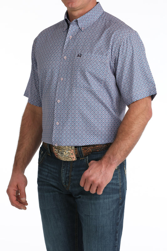 Man wearing a patterned short-sleeve shirt and jeans on a white background