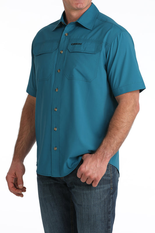 Man wearing a teal short-sleeve shirt with button details on a white background