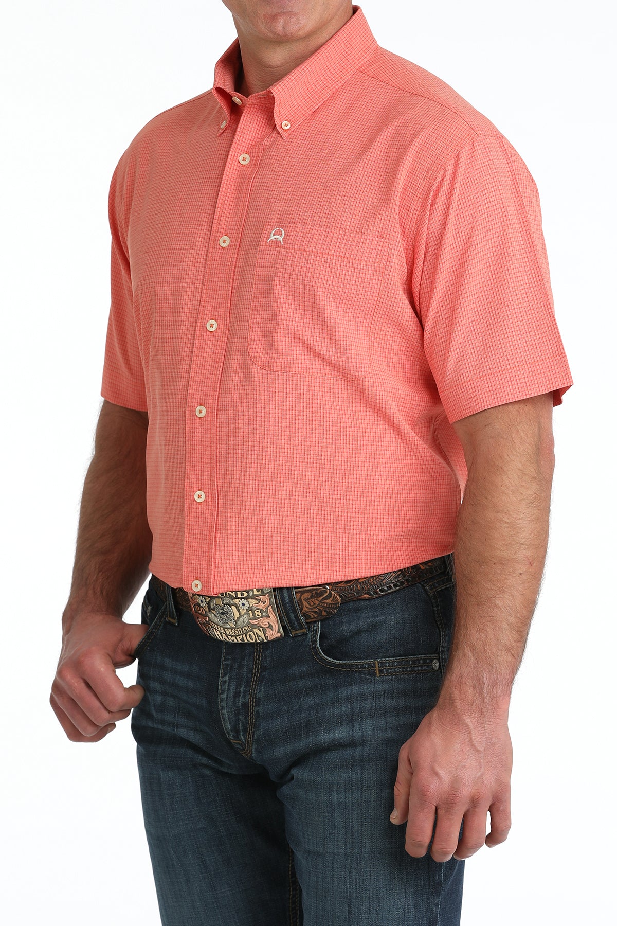 Man wearing a coral patterned short-sleeve shirt and blue jeans on a white background