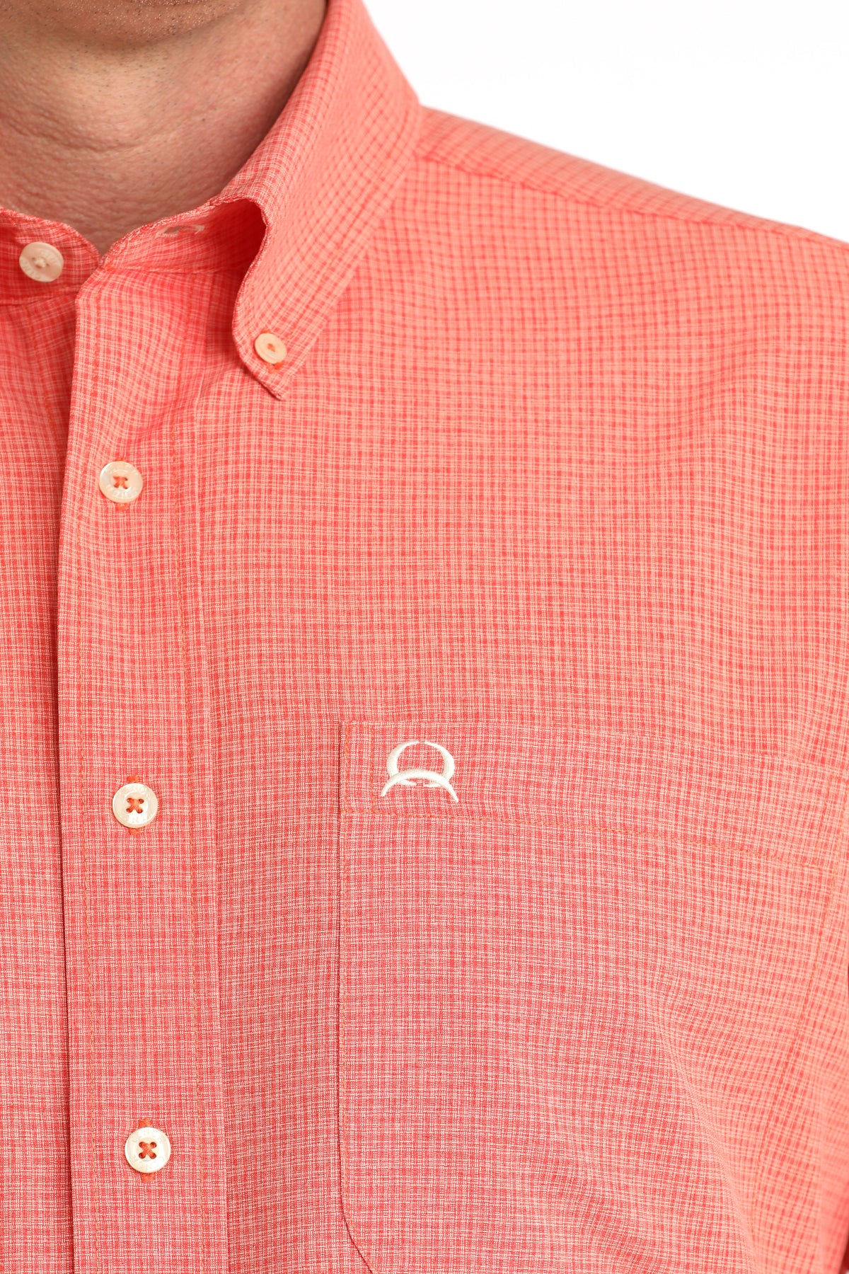 Close-up of a red checkered shirt with a small logo on a white background