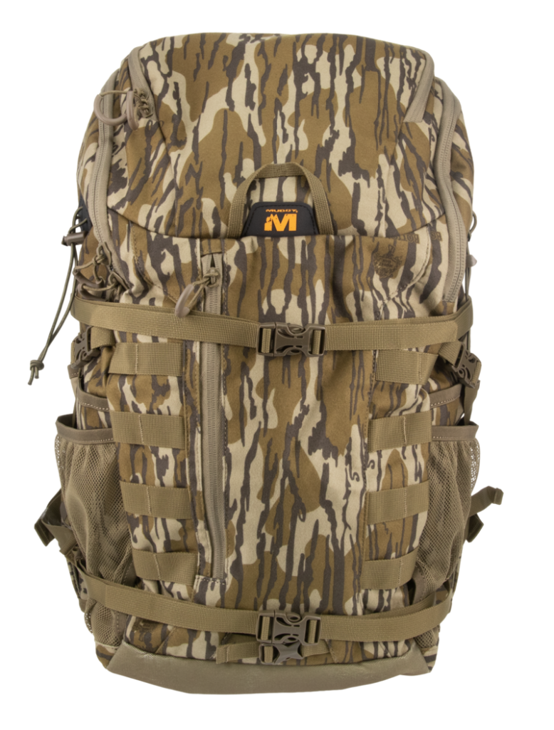 A large tactical backpack in a woodland camouflage pattern with brown, tan, and gray tones, featuring multiple compression straps, side mesh pockets, and a black and orange logo patch on the front.