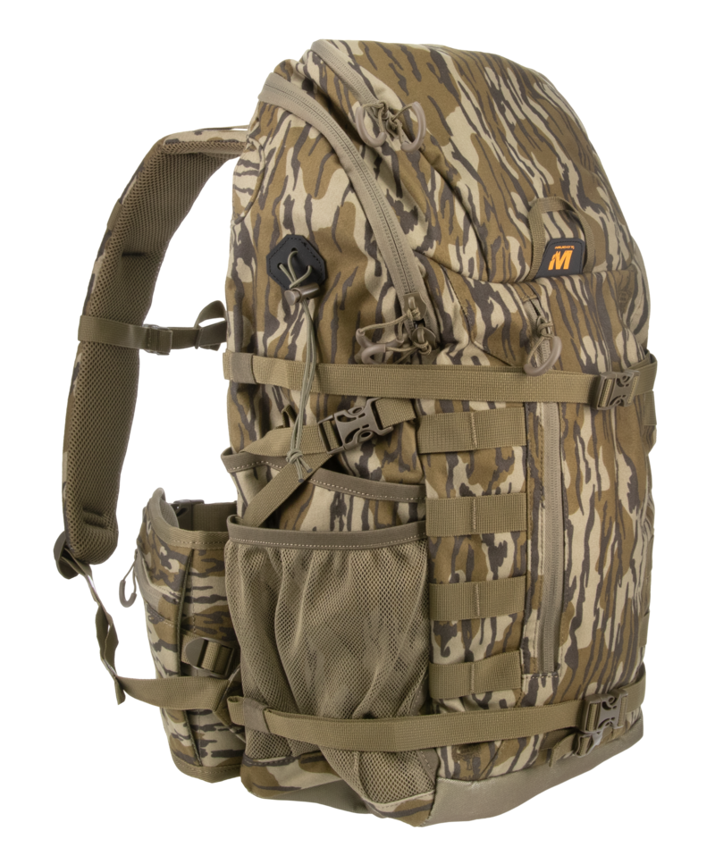 A camouflage backpack in a brown and tan woodland pattern, featuring multiple zippered compartments, webbing straps, and a side mesh pocket, shown against a plain white background.