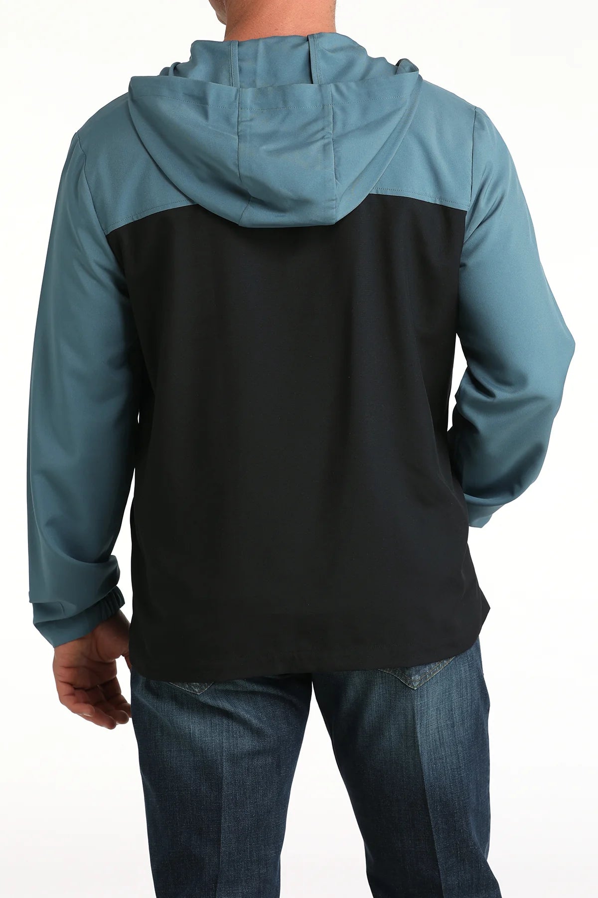 Man wearing a colorblock hooded jacket with teal sleeves and black back, shown from behind