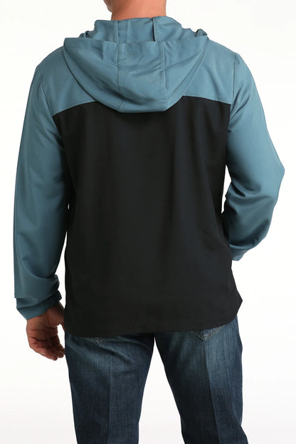 Man wearing a colorblock hooded jacket with teal sleeves and black back, shown from behind