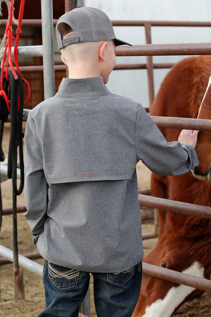 Young boy in grey shirt and cap petting horse at ranch fence, western jeans visible