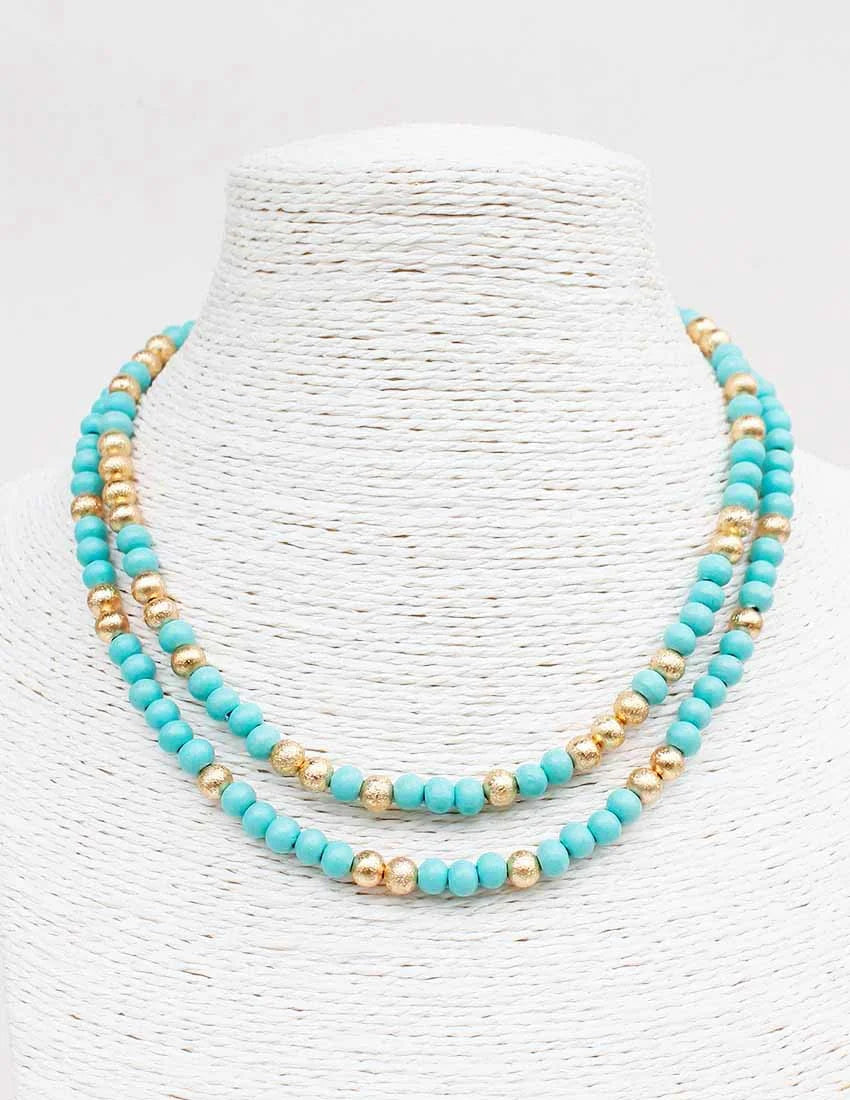 Turquoise and gold beaded necklace on a white textured background
