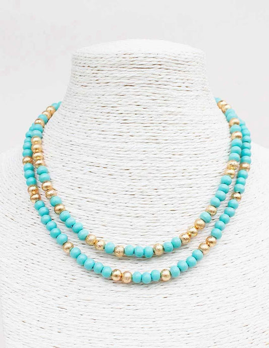 Turquoise and gold beaded necklace on a white textured background