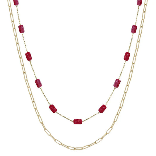 Two layered necklaces with gold chains and red beads on a white background