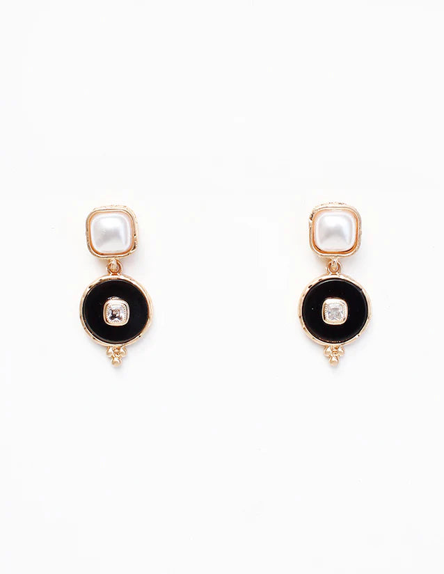 Pair of earrings with black circular designs and pearl-like centers on a white background