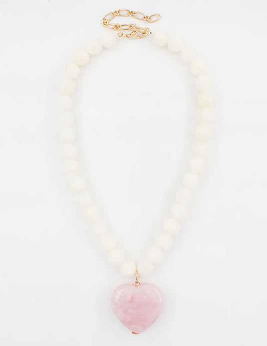 A beaded necklace featuring a strand of matte white round beads with a polished pink heart-shaped stone pendant, finished with a gold-tone clasp.