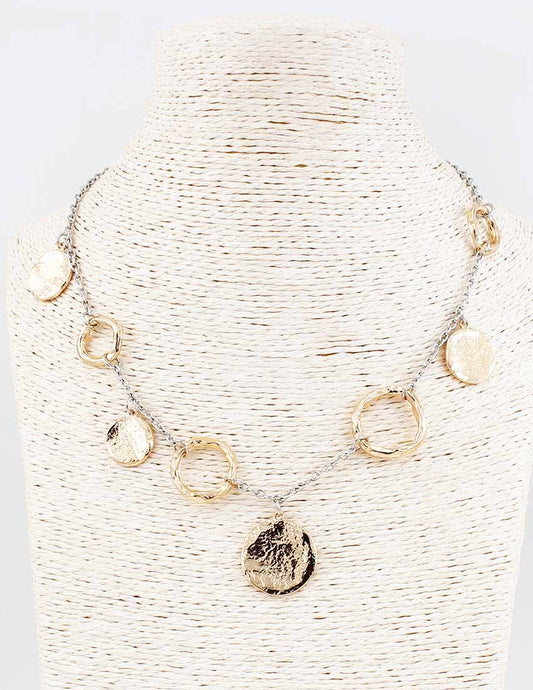 Necklace with gold and silver pendants on a textured white stand