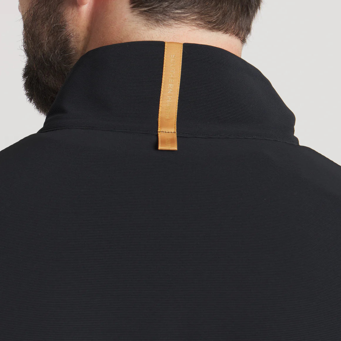 Close-up of black jacket collar with tan leather loop detail on back