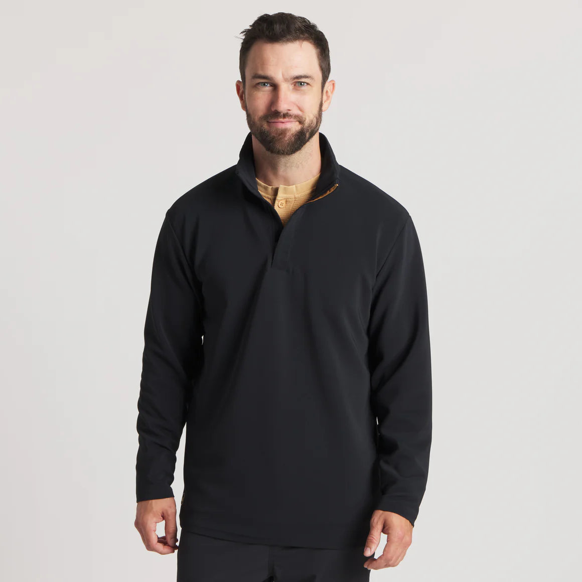Man wearing a black long sleeve pullover with a quarter zip collar, neutral background