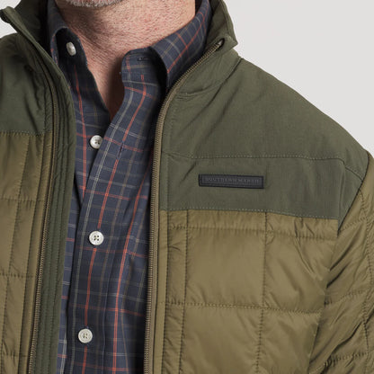 Close-up of olive green quilted men's jacket over plaid button-up shirt
