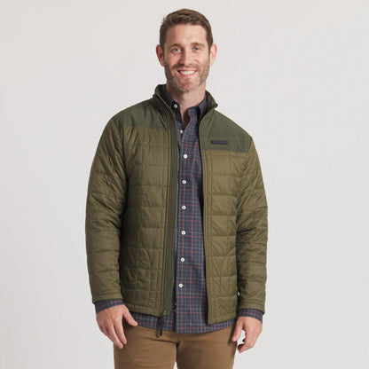Man wearing olive green quilted jacket over plaid shirt, outdoor casual style