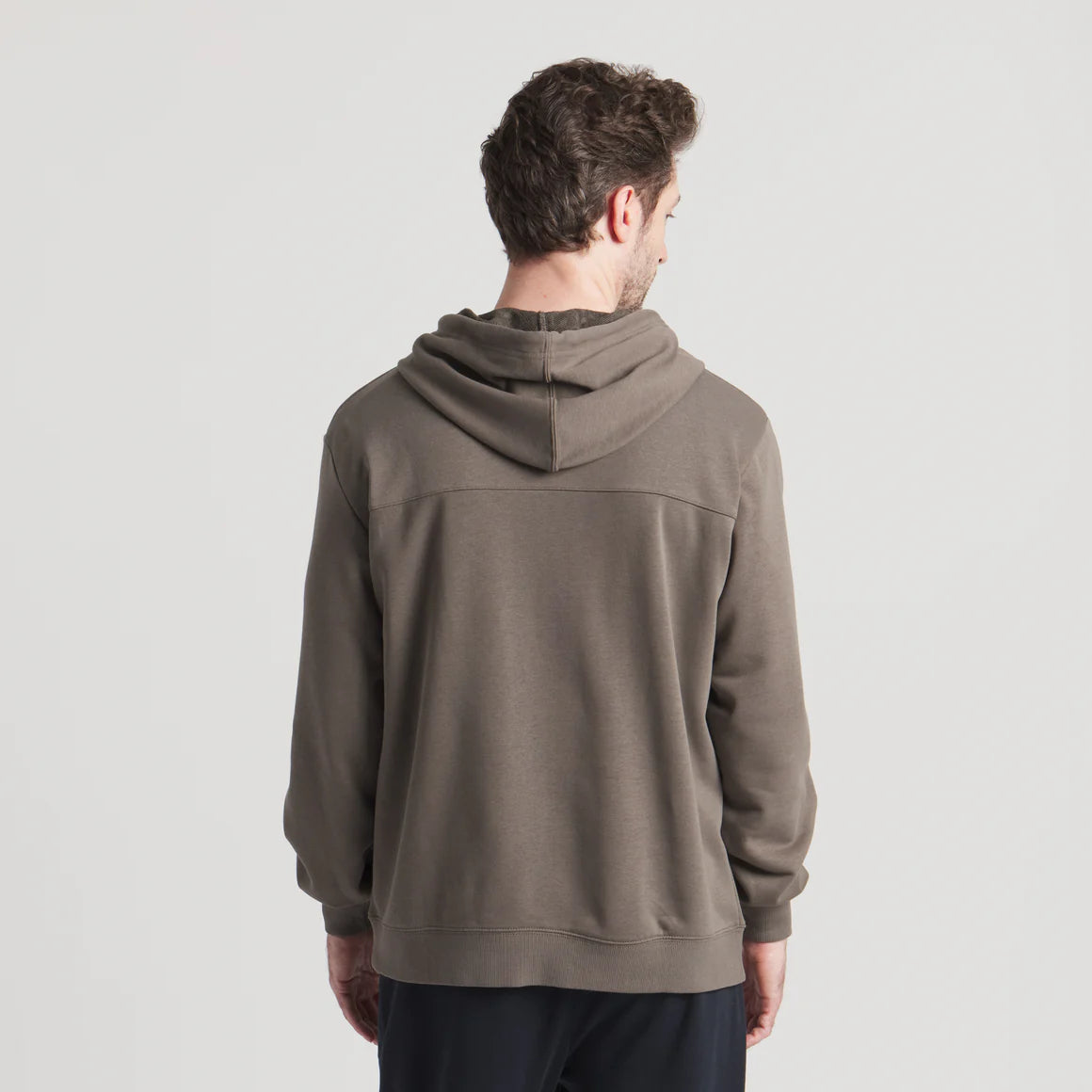 Back view of a man wearing a taupe hooded sweatshirt with long sleeves