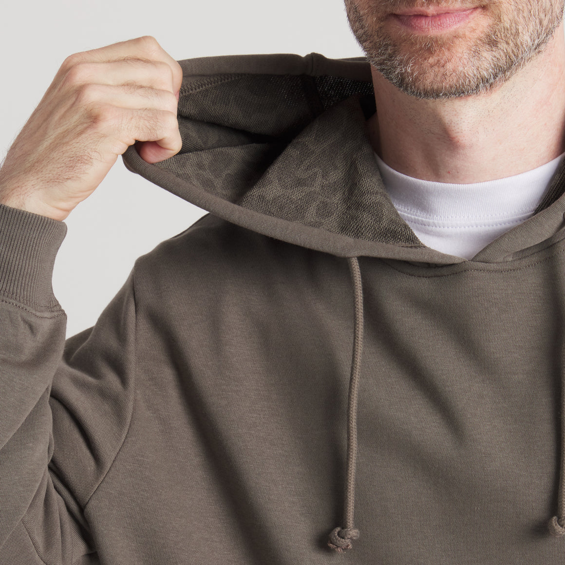 Close-up of man wearing olive green hoodie with drawstring and textured hood lining