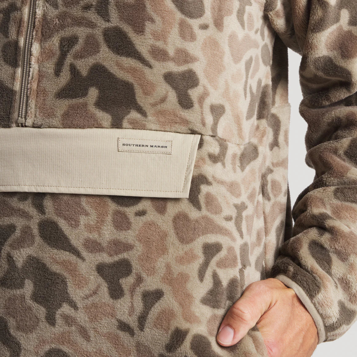 Close-up of hand in pocket of brown leopard print fleece pullover with zipper and beige accent