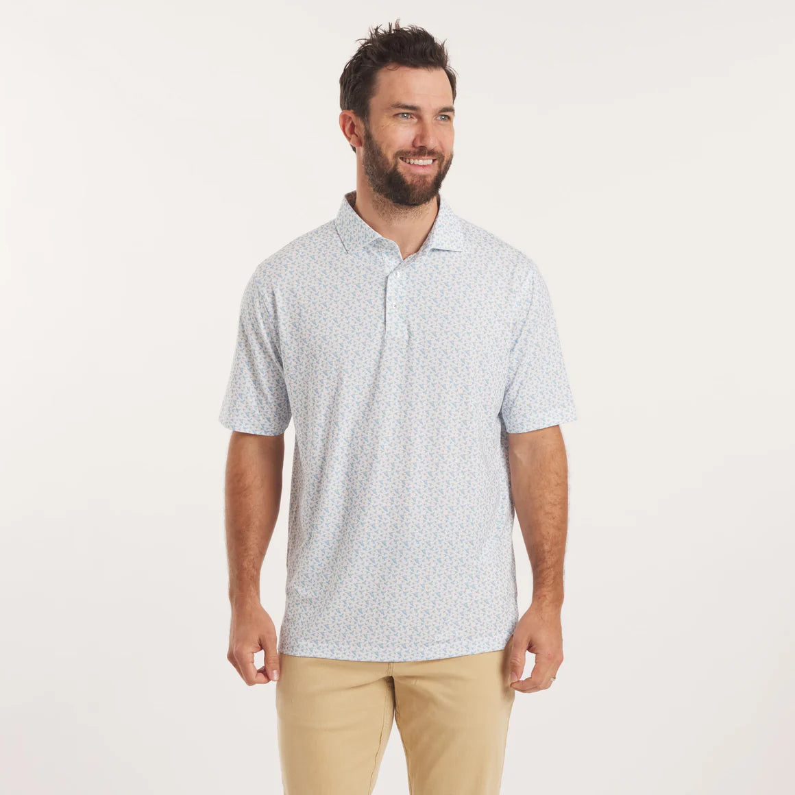 Man wearing a light blue patterned polo shirt and beige pants on a white background