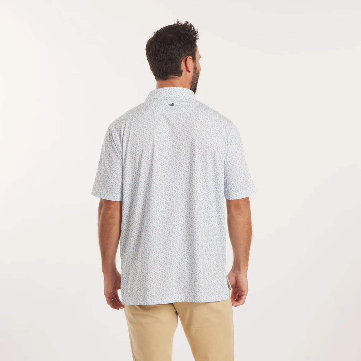 Man wearing a light blue patterned shirt and beige pants on a white background
