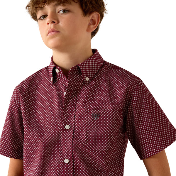 Child wearing a maroon patterned shirt on a white background