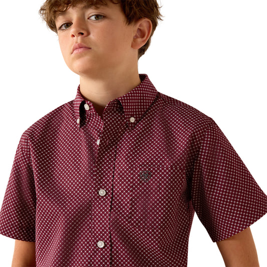 Child wearing a maroon patterned shirt on a white background