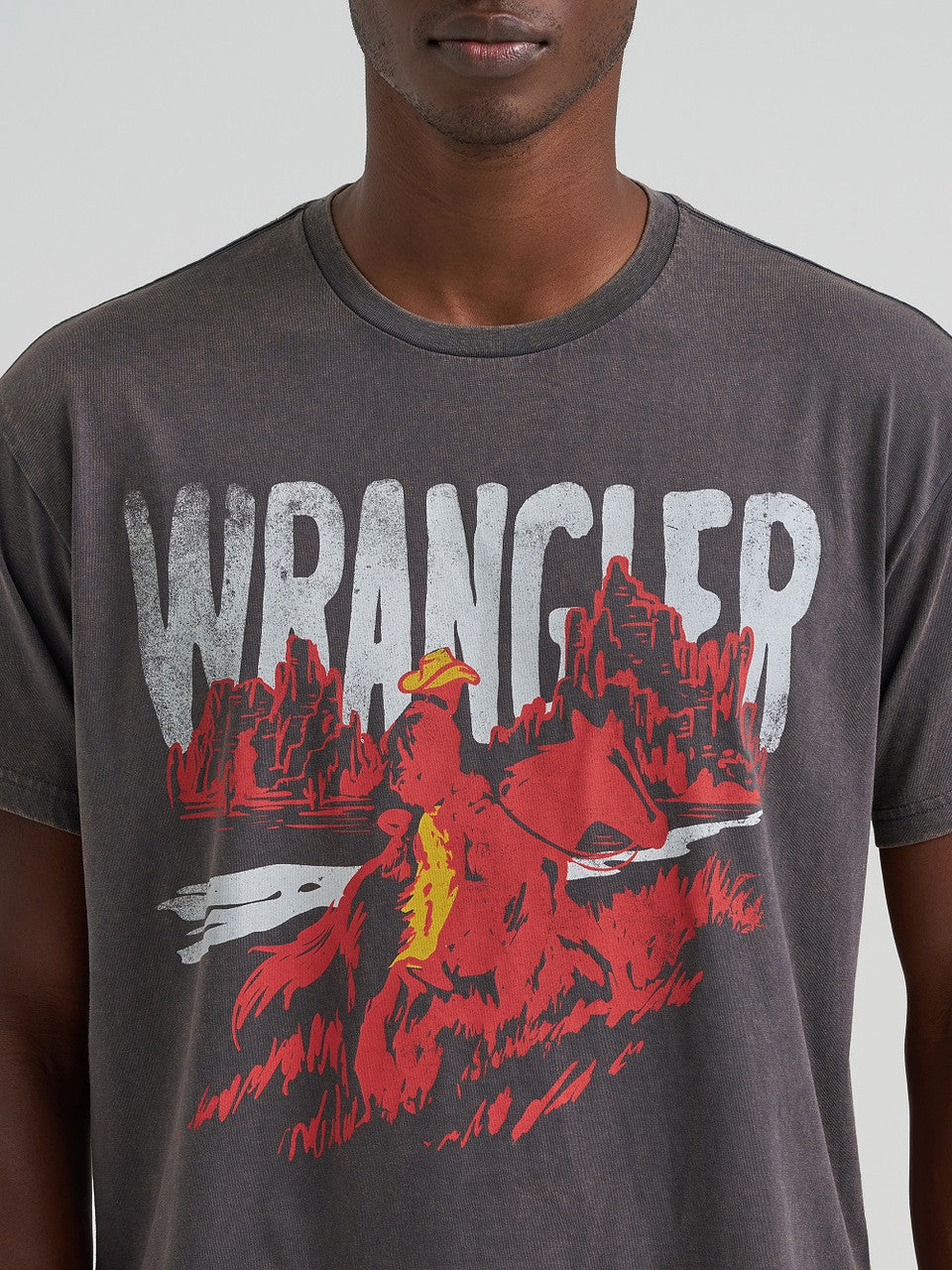Man wearing a Wrangler t-shirt with a graphic design on a plain background