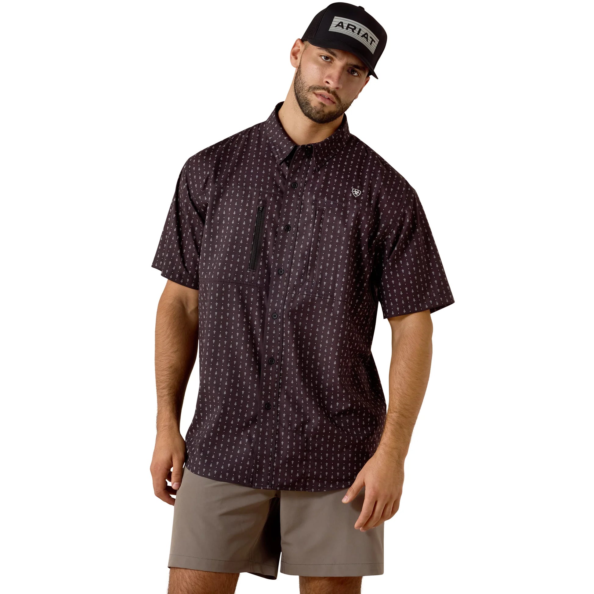Man wearing a patterned shirt and cap with 'Ariat' branding on a white background