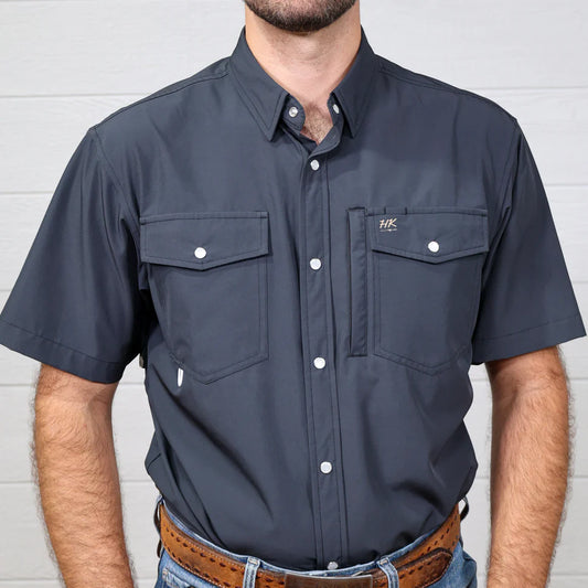Man wearing a navy short-sleeve shirt with a brand logo against a light gray background