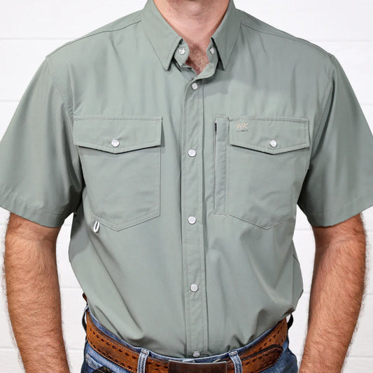 Man wearing a green short-sleeve shirt with pockets on a white background