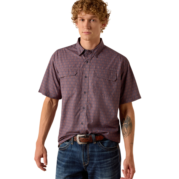 Man wearing a patterned short-sleeve shirt and jeans on a white background