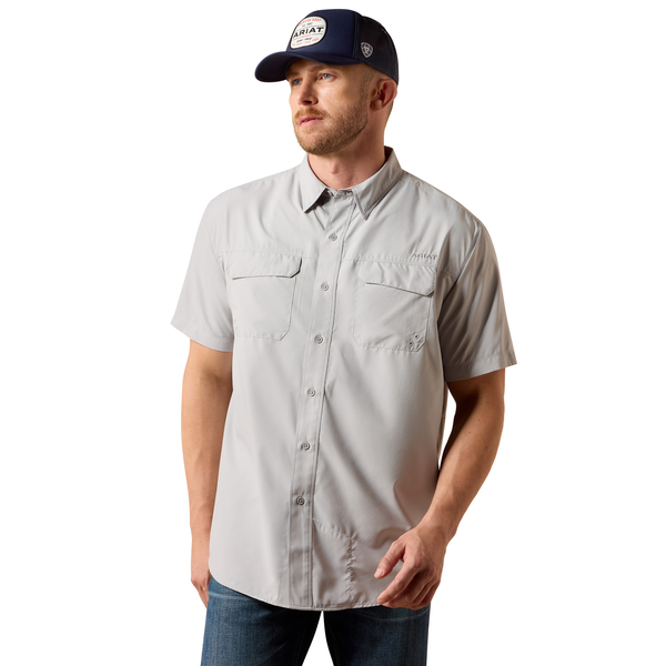 Man wearing a light gray button-up shirt and navy cap on a white background