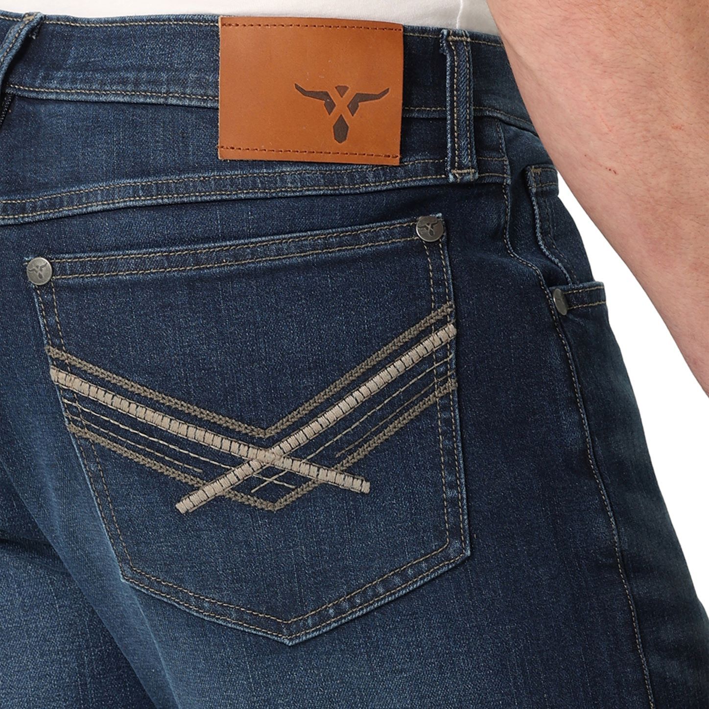 Close-up of blue jeans with a brown leather patch on a white background