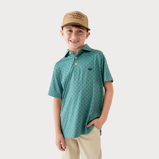 Child wearing a green patterned polo shirt and beige cap on a white background