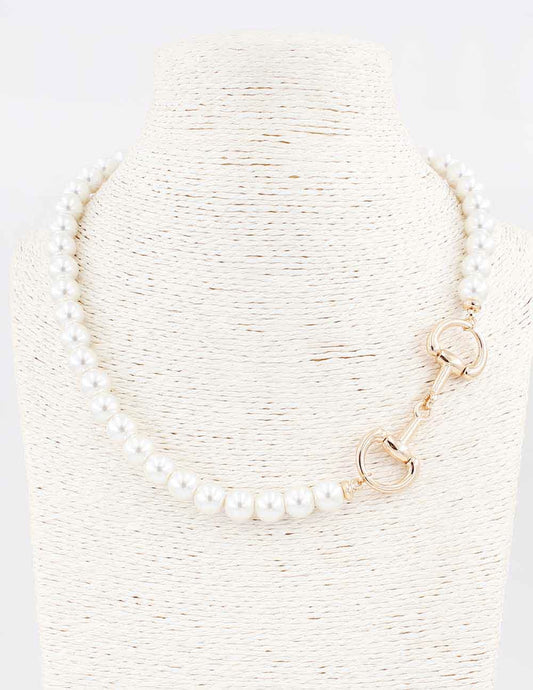 Pearl necklace with gold clasp on a textured white background