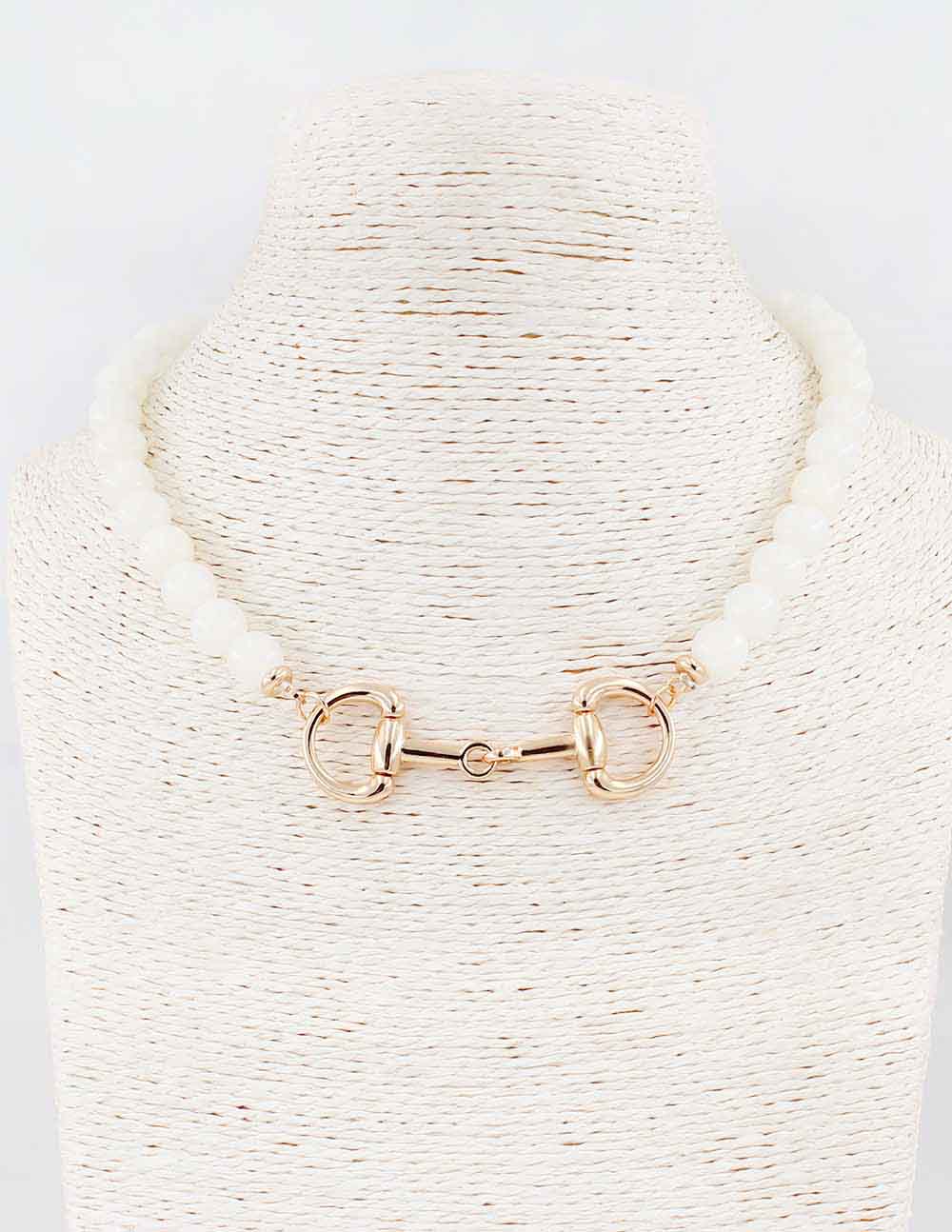 Gold horsebit necklace on a textured white stand