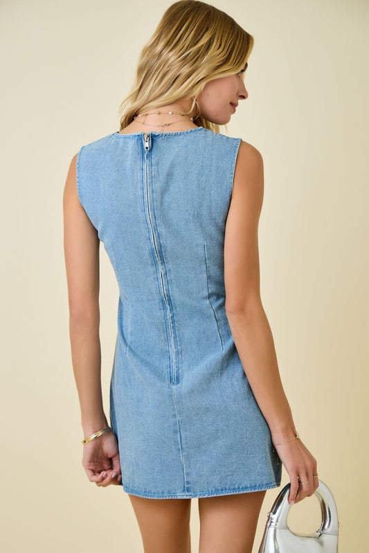 Woman wearing a light blue denim dress against a beige background