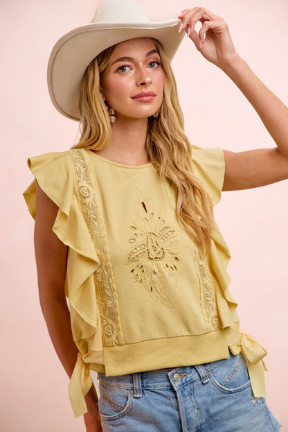 Woman wearing a yellow top with ruffled sleeves and denim shorts against a pink background