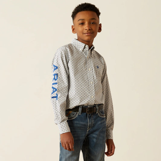 Young boy wearing a patterned shirt with 'Ariat' branding on a beige background