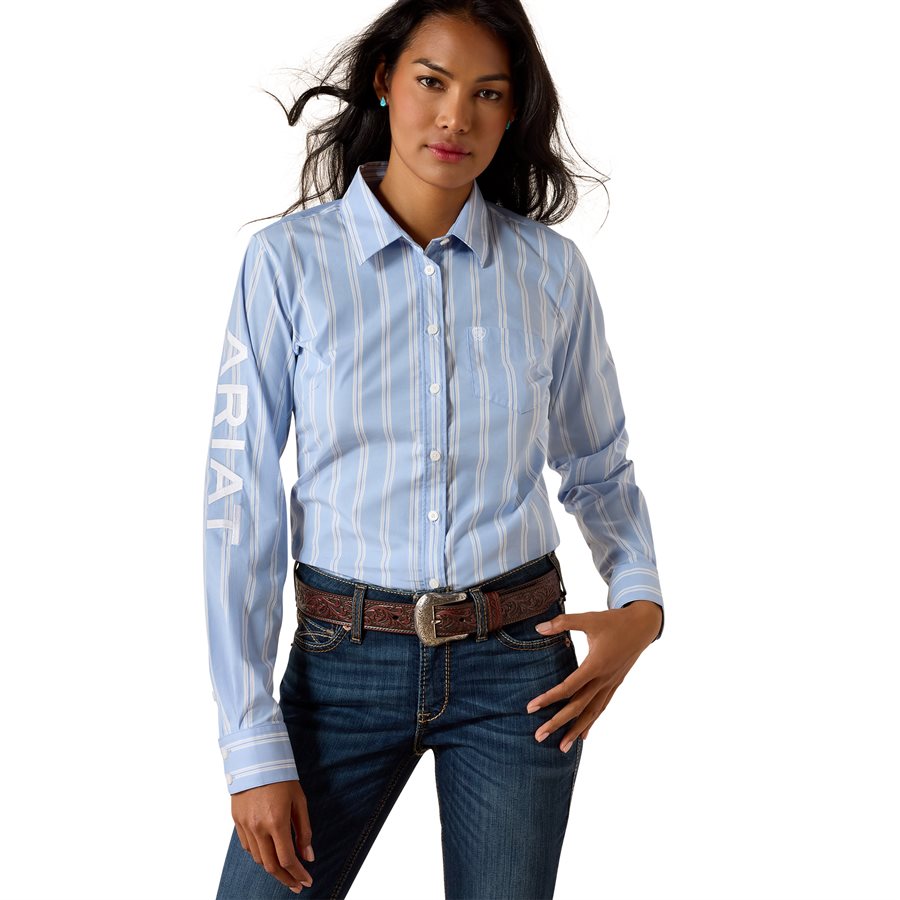 Woman in light blue striped western shirt with ARIAT text on sleeve and blue jeans