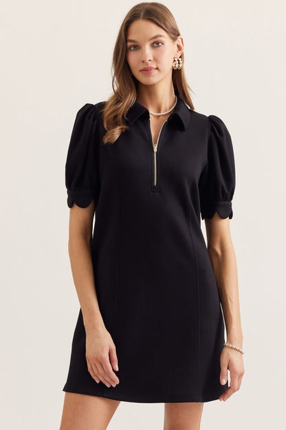 Woman wearing a black dress with puff sleeves on a light background