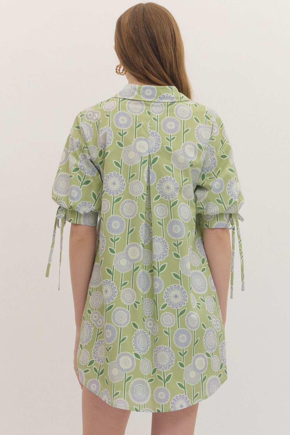 Woman wearing a green floral dress against a white background