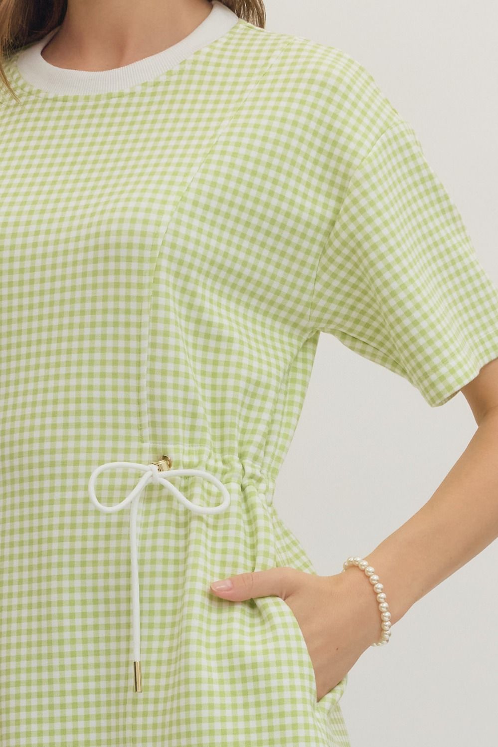 Green checkered dress with a white drawstring on a plain background
