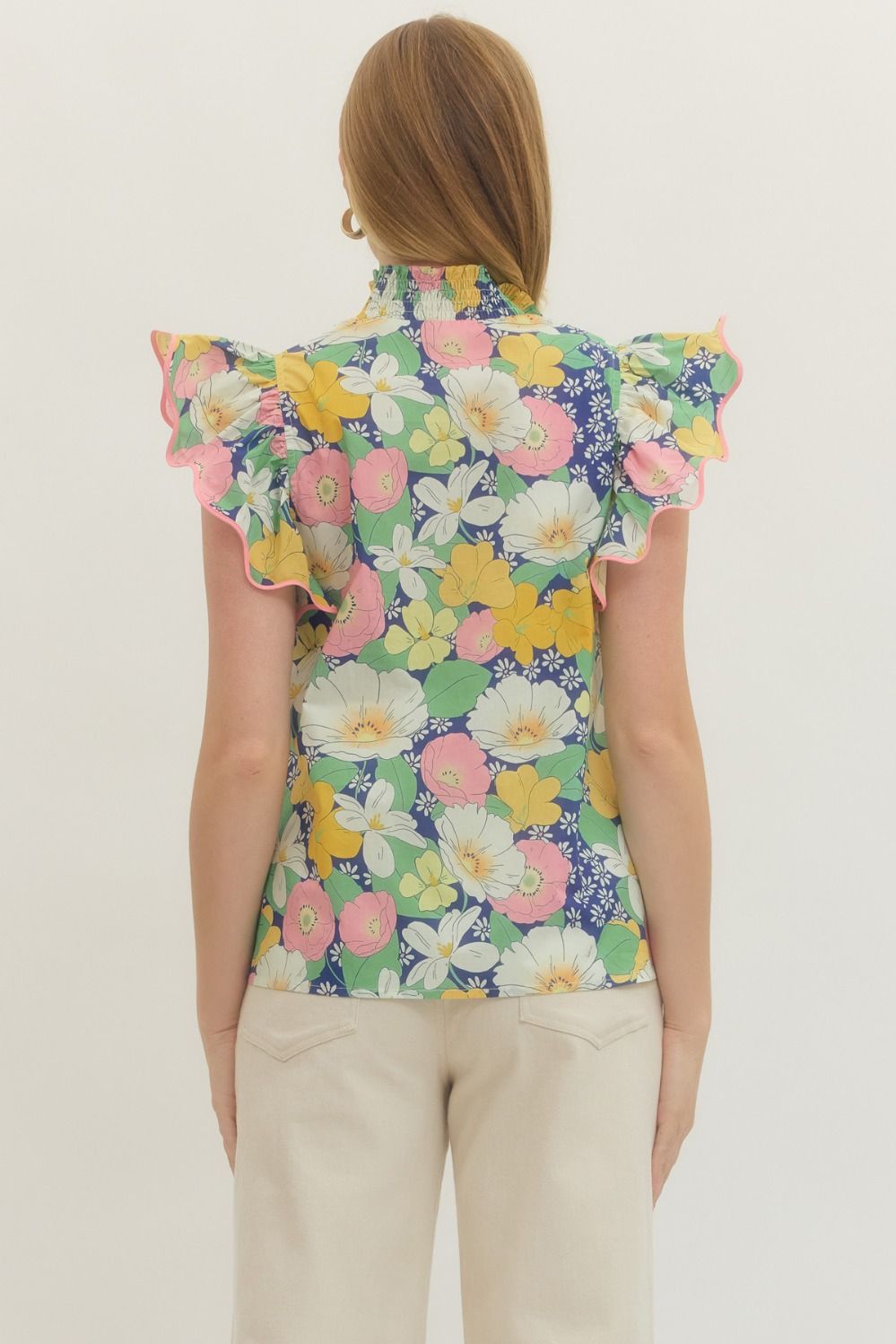 Woman wearing a colorful floral sleeveless top on a plain background