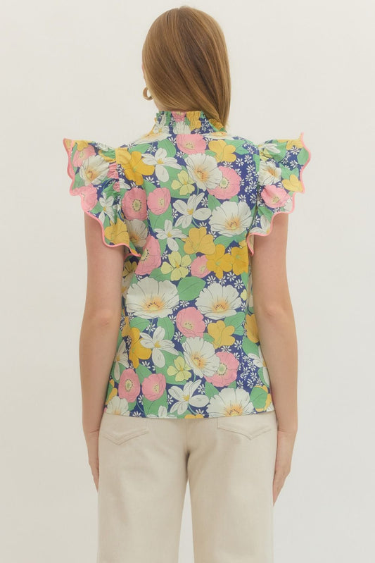 Woman wearing a colorful floral sleeveless top on a plain background